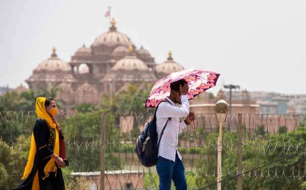 people using shawls and umbrellas to protect from heat