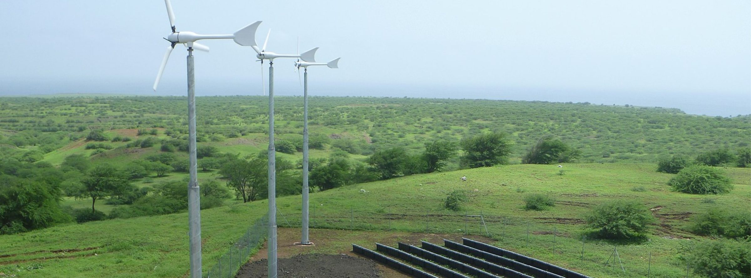 three small wind turbine windmills with an open field in the background